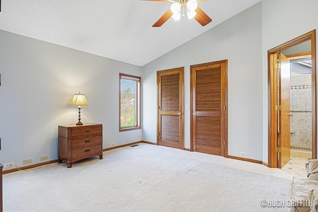 carpeted bedroom featuring a ceiling fan, baseboards, ensuite bathroom, two closets, and vaulted ceiling