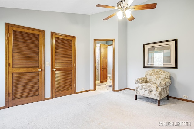 sitting room with a ceiling fan, light carpet, baseboards, and lofted ceiling
