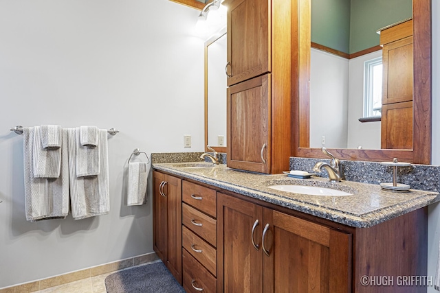 bathroom featuring double vanity, baseboards, and a sink