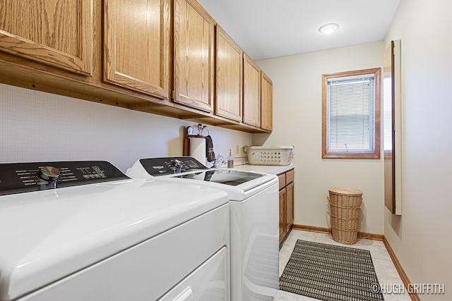 washroom featuring cabinet space, washer and clothes dryer, baseboards, and light tile patterned floors