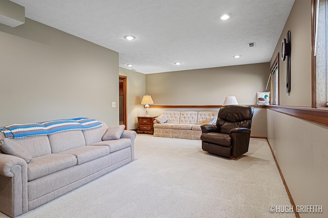 carpeted living area with a textured ceiling, visible vents, and recessed lighting