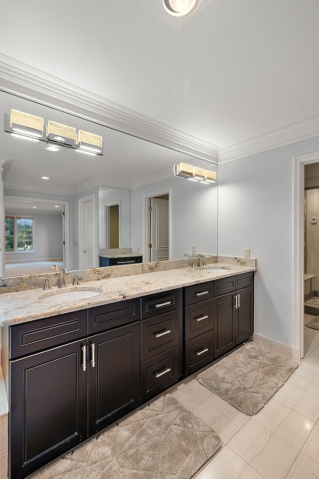 full bath featuring a sink, double vanity, crown molding, and baseboards