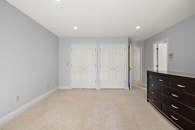 unfurnished bedroom featuring baseboards, multiple closets, and recessed lighting