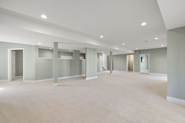 finished below grade area featuring stairway, light carpet, baseboards, and recessed lighting