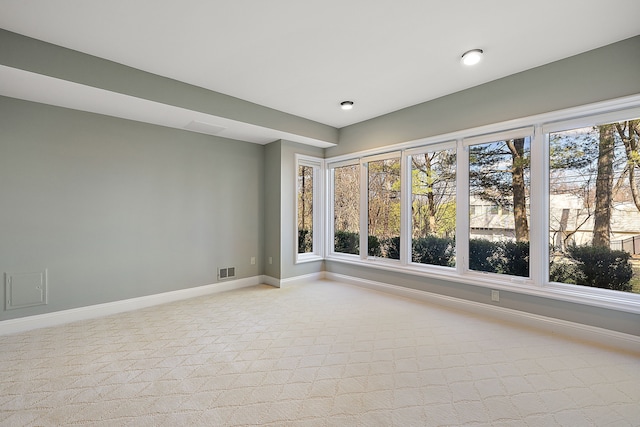 empty room featuring light colored carpet, plenty of natural light, visible vents, and baseboards