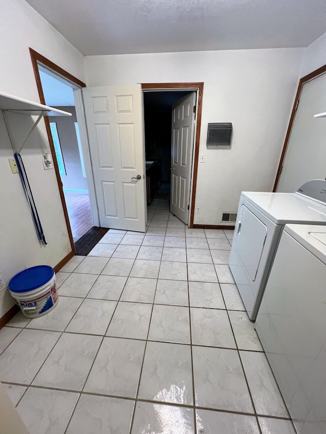clothes washing area featuring laundry area, washer and clothes dryer, visible vents, and baseboards