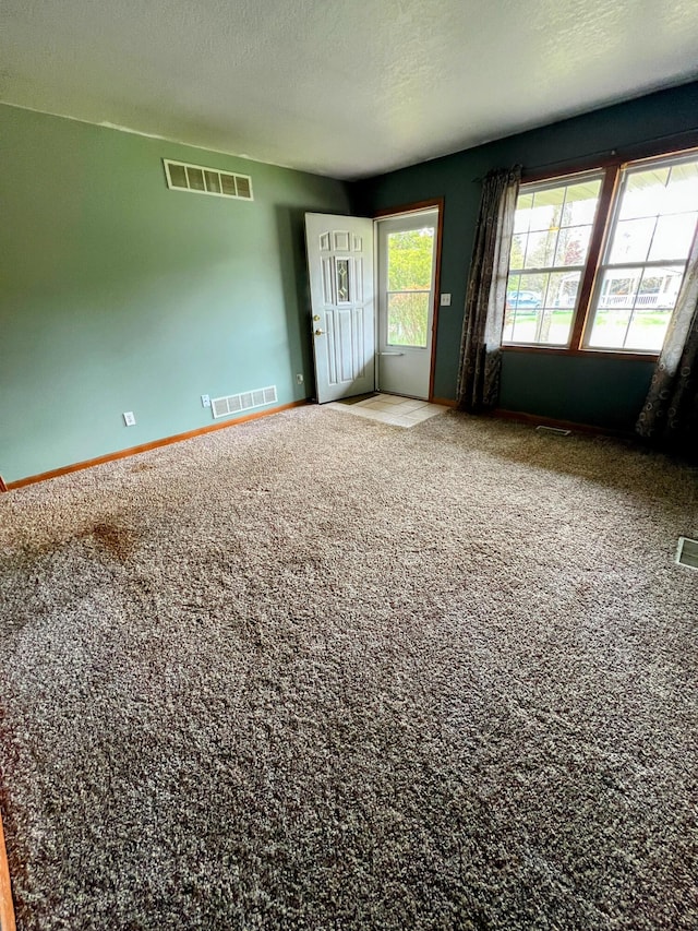 empty room with baseboards, visible vents, and carpet