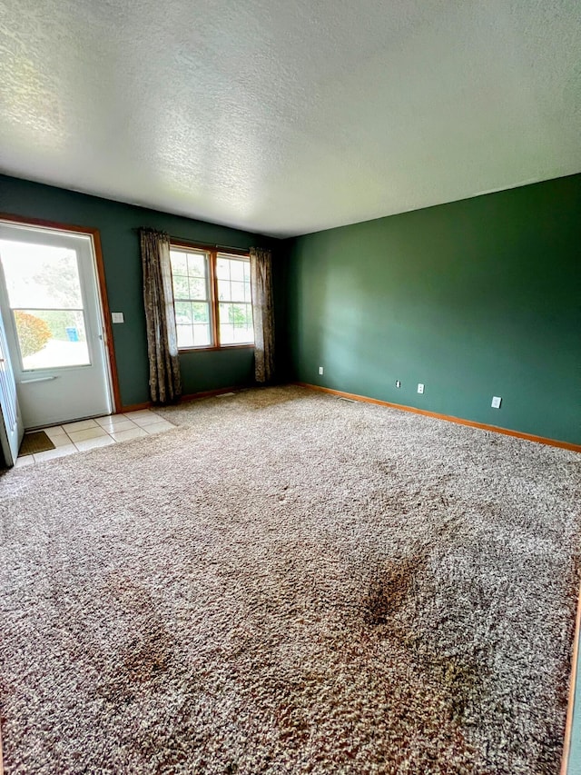 empty room with a textured ceiling, light carpet, and baseboards