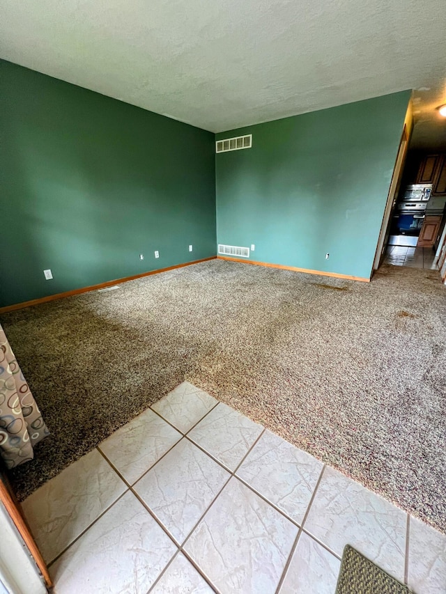 carpeted empty room featuring baseboards, visible vents, and a textured ceiling
