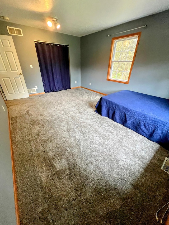 bedroom with baseboards, visible vents, and carpet
