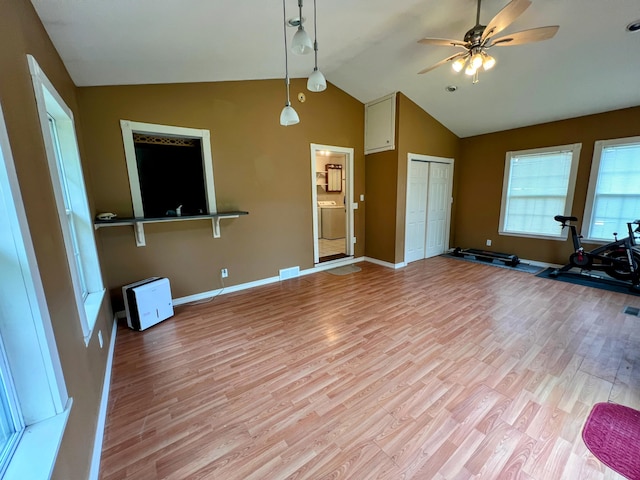 interior space featuring a ceiling fan, high vaulted ceiling, light wood-type flooring, baseboards, and washer / clothes dryer