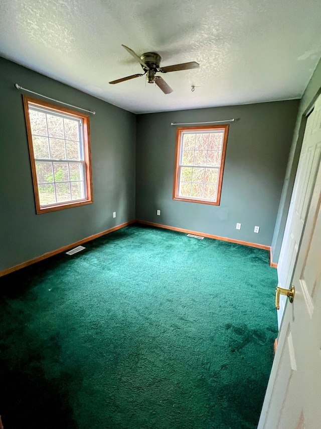 spare room featuring a textured ceiling, baseboards, a ceiling fan, and carpet