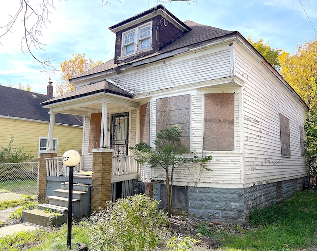 view of front of home featuring a shingled roof, a porch, and fence