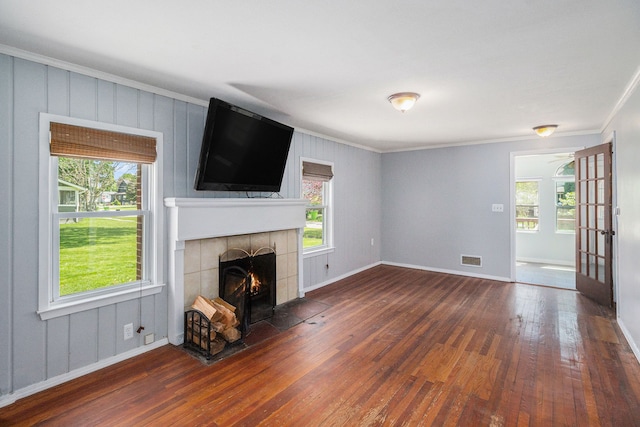 unfurnished living room with a fireplace, hardwood / wood-style floors, ornamental molding, healthy amount of natural light, and baseboards