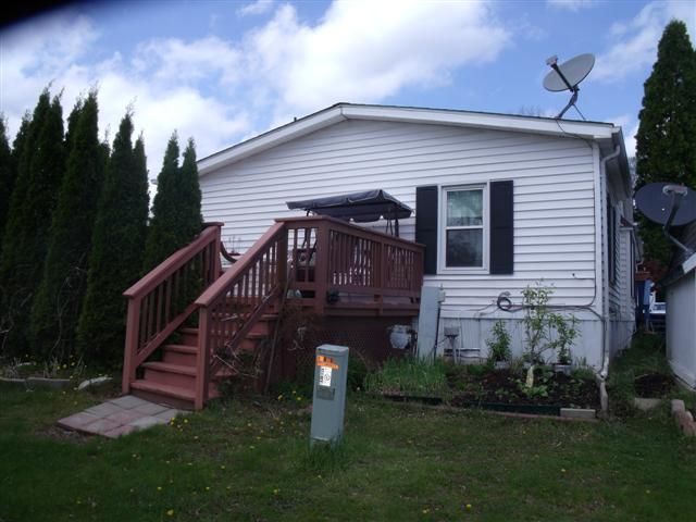 back of property featuring stairway, a deck, and a lawn