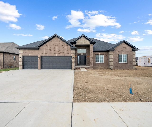 view of front facade featuring concrete driveway, an attached garage, a shingled roof, and brick siding