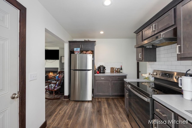 506 Fairview Ave NE, Grand Rapids, MI 49503 - kitchen with under cabinet range hood, dark brown cabinetry, appliances with stainless steel finishes, and dark wood finished floors