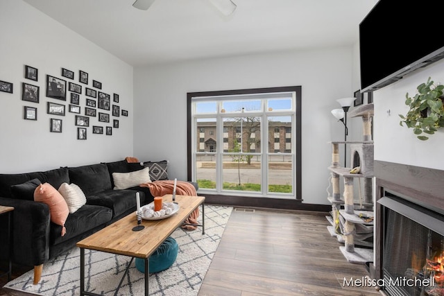 506 Fairview Ave NE, Grand Rapids, MI 49503 - living area with visible vents, ceiling fan, a lit fireplace, and wood finished floors
