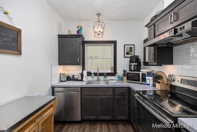 506 Fairview Ave NE, Grand Rapids, MI 49503 - kitchen featuring under cabinet range hood, an inviting chandelier, a sink, backsplash, and appliances with stainless steel finishes