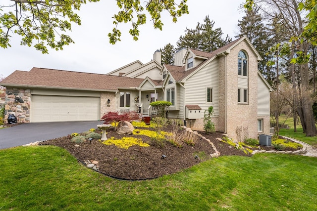 view of front of property with asphalt driveway, a garage, a front lawn, central AC, and brick siding