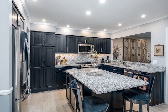 kitchen with stainless steel appliances, a sink, a kitchen breakfast bar, a center island, and tasteful backsplash