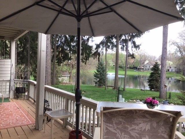 wooden deck featuring a water view and a lawn