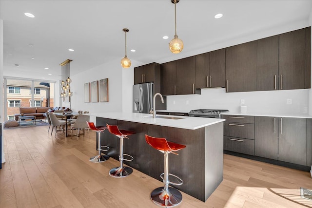 2809 Brush St, Detroit, MI 48201 - kitchen with light wood-style flooring, a breakfast bar area, a sink, stainless steel fridge with ice dispenser, and an island with sink
