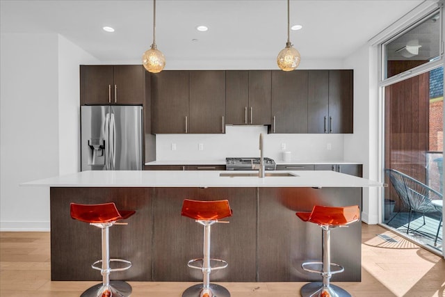 2809 Brush St, Detroit, MI 48201 - kitchen featuring baseboards, a breakfast bar, stainless steel fridge, a center island with sink, and light countertops