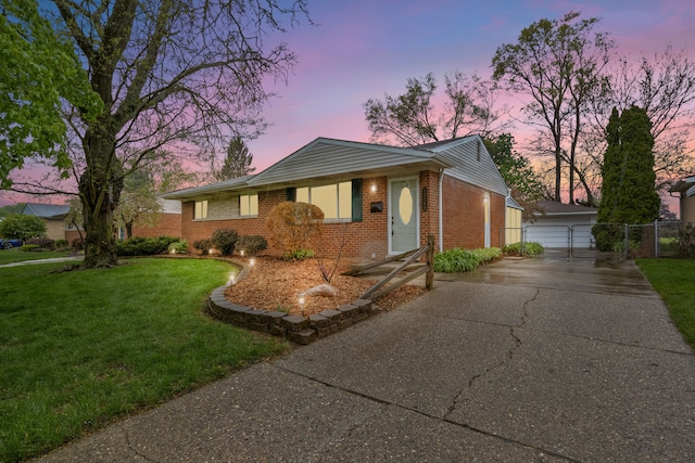 ranch-style house featuring a yard, an outbuilding, brick siding, fence, and a detached garage