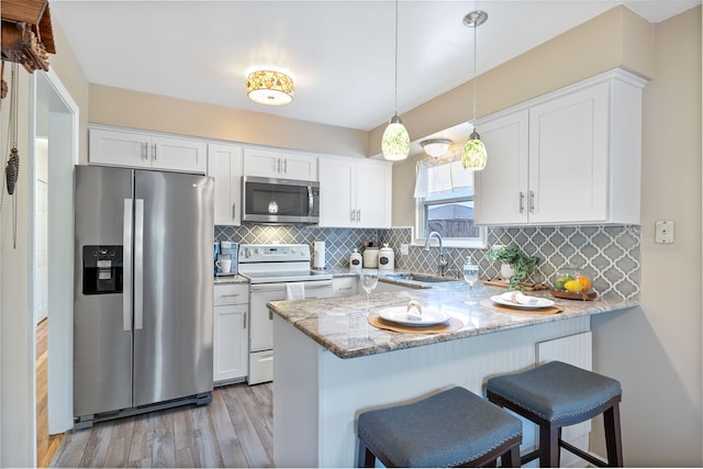 kitchen featuring a sink, a peninsula, stainless steel appliances, white cabinets, and light wood-type flooring