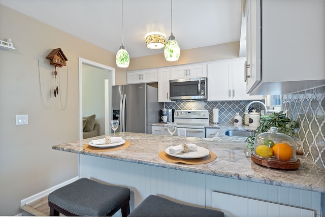 kitchen with a sink, stainless steel appliances, white cabinets, tasteful backsplash, and light stone counters