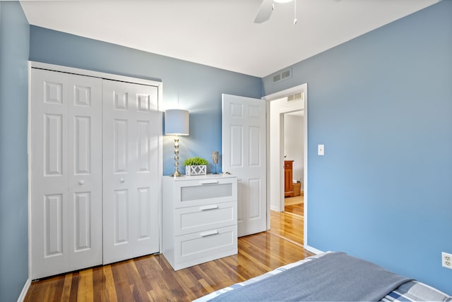 bedroom with a ceiling fan, a closet, visible vents, and wood finished floors