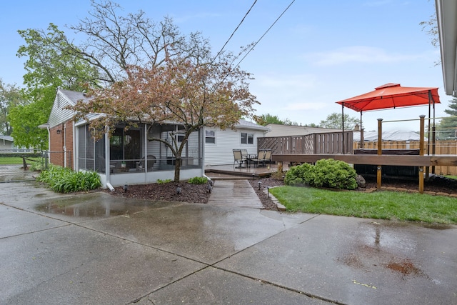 back of house with a gazebo, a wooden deck, a sunroom, and fence