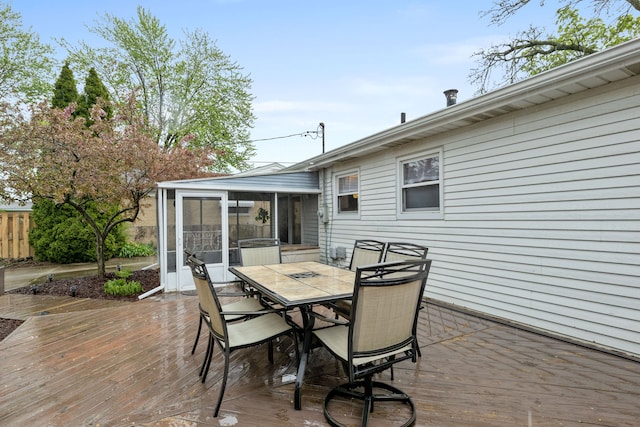 wooden deck featuring a sunroom and outdoor dining space