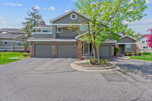 view of front of home with a garage, a chimney, brick siding, and driveway