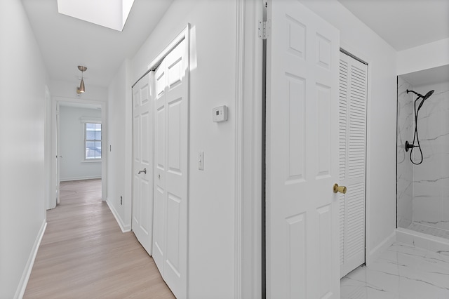 corridor with baseboards and a skylight