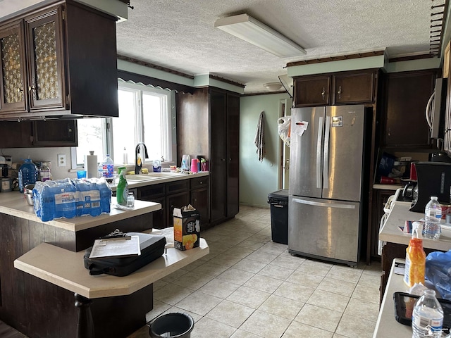 kitchen featuring a sink, stainless steel appliances, a textured ceiling, light countertops, and dark brown cabinets
