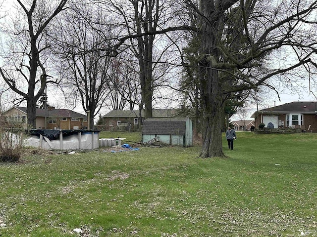 view of yard featuring a covered pool, a storage shed, and an outdoor structure