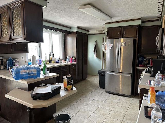 kitchen with freestanding refrigerator, light countertops, a sink, and a textured ceiling