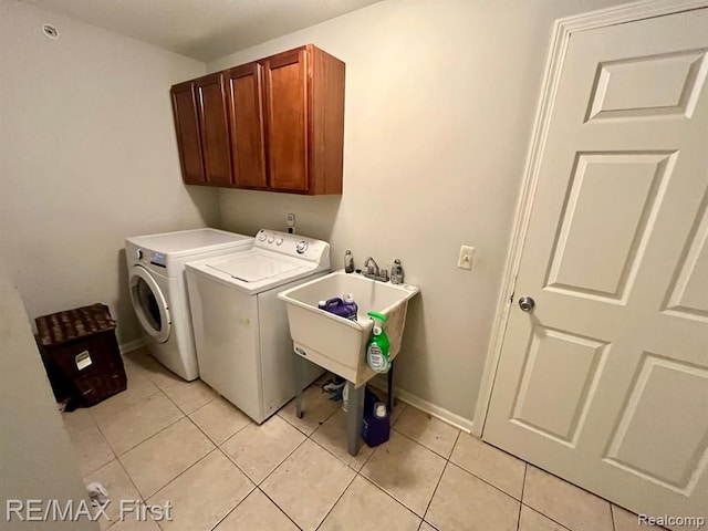 clothes washing area with washer and dryer, cabinet space, light tile patterned floors, and baseboards