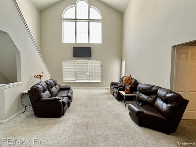 carpeted living area with high vaulted ceiling, healthy amount of natural light, and baseboards