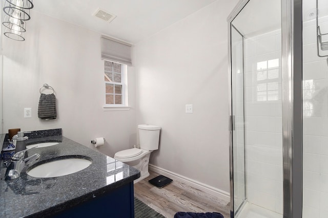 full bath with wood finished floors, a shower stall, toilet, double vanity, and baseboards