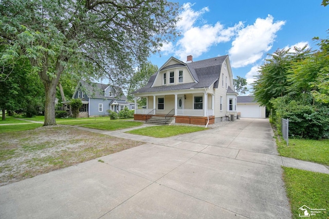 view of front of house featuring a porch, a detached garage, a gambrel roof, an outbuilding, and a front lawn