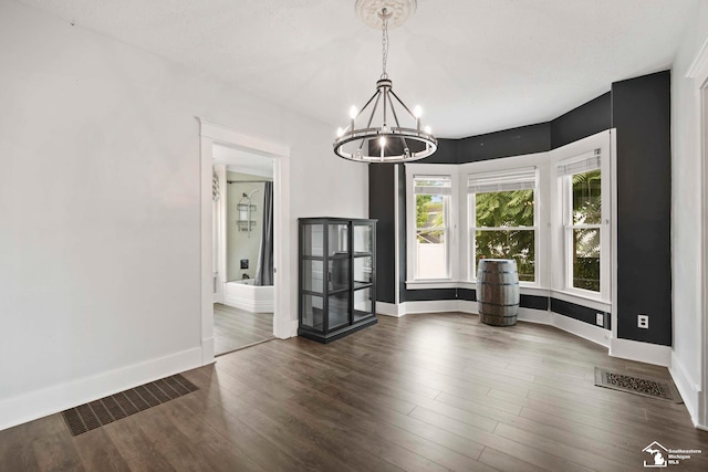 unfurnished dining area featuring baseboards, a notable chandelier, and visible vents