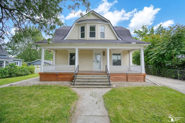 view of front of home with a front lawn, a gambrel roof, roof with shingles, and covered porch