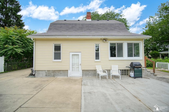 rear view of house with fence, a patio, a shingled roof, and a chimney