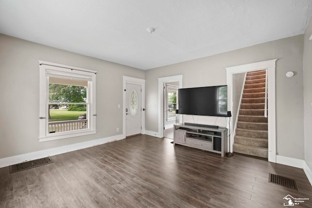 unfurnished living room with visible vents, baseboards, dark wood-type flooring, and stairs