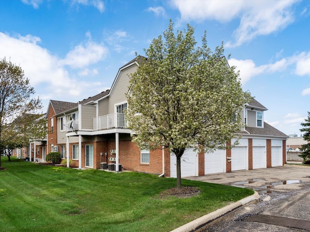 exterior space with central air condition unit, brick siding, driveway, a residential view, and a lawn