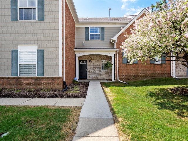 view of exterior entry featuring a yard and brick siding