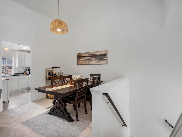 dining area with light colored carpet and high vaulted ceiling